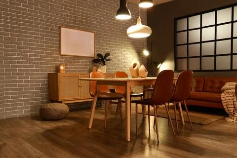 Interior of modern dining room with glowing lamps, sofa and table Stock Photos