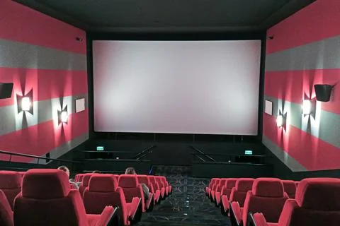 Interior of a modern empty red cinema hall in theater with armchairs and ligh Stock Photos