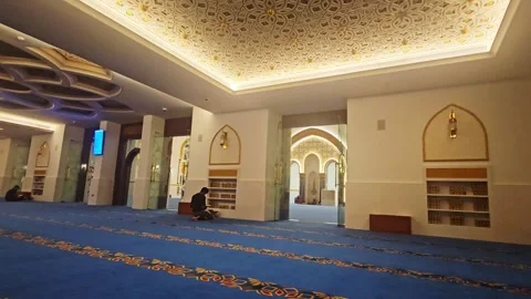 Interior of a modern mosque featuring a spacious prayer hall with vibrant blue Stock Footage 338258989