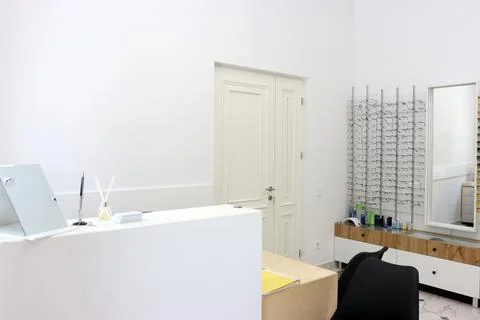 Interior of a modern optical store with a reception desk, eyeglass display st Stock Photos