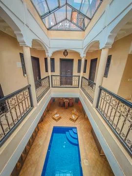 Interior of a Moroccan riad with a small pool in the middle and glass roof 스톡 사진