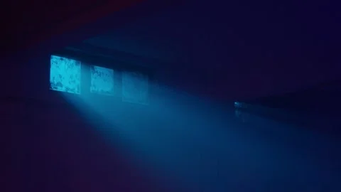 Interior night shot of an empty basement. Blue light, dirty window and fan.  Stock Footage 236090273