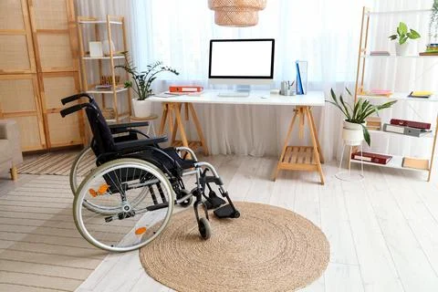 Interior of office with shelf units, workplace and wheelchair Stock Photos