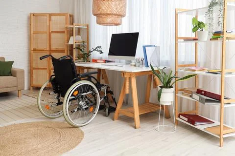 Interior of office with shelf units, workplace and wheelchair Stock Photos
