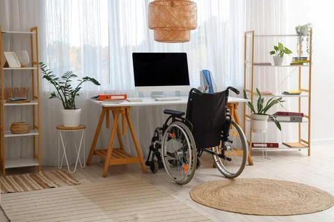 Interior of office with shelf units, workplace and wheelchair Stock Photos