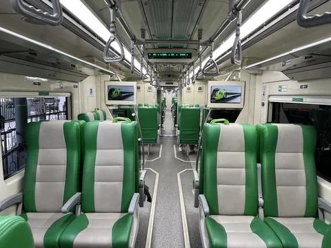 Interior of a passenger train car featuring rows of seats and arm rest Stock Photos