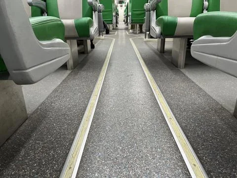 Interior of a passenger train car featuring rows of seats and arm rest Stock Photos