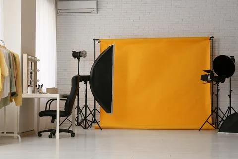 Interior of photo studio with yellow backdrop, makeup table and lighting equi Stock Photos