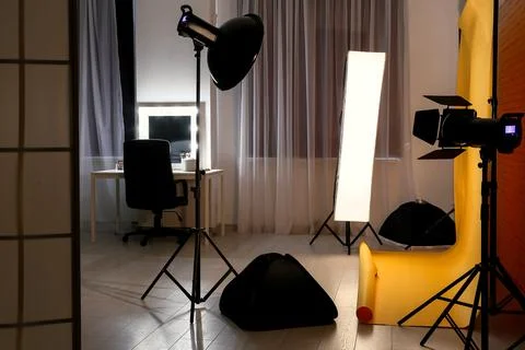 Interior of photo studio with yellow backdrop, makeup table and lighting equi Stock Photos