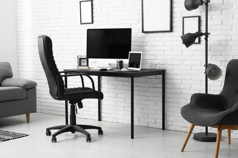 Interior of programmer's office with workplace, armchair and lamp 库存照片