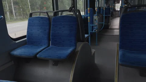 Interior of public bus with blue seats and visible aisle in urban setting Vídeos de archivo 343689558