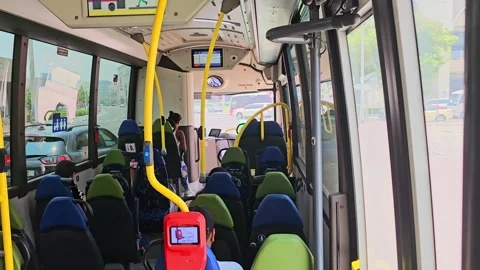 Interior of a public bus with rows of blue and green seats. Yellow poles Video stock 312002986