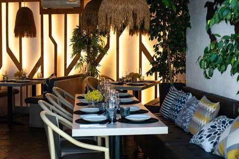 Interior of a restaurant with set table and comfy bench with pillows Stock Photos