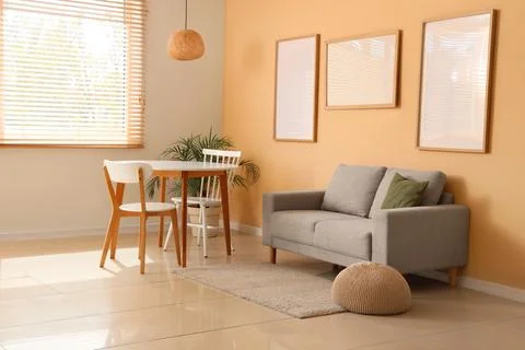 Interior of room with blank frames, sofa and dining table Фото