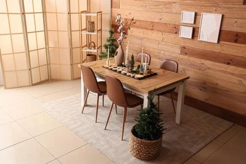Interior of room with dining table, Christmas trees and burning candles Stock Photos