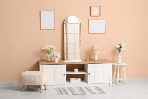 Interior of room with mirror, blank frames and artificial flowers Fotos Stock