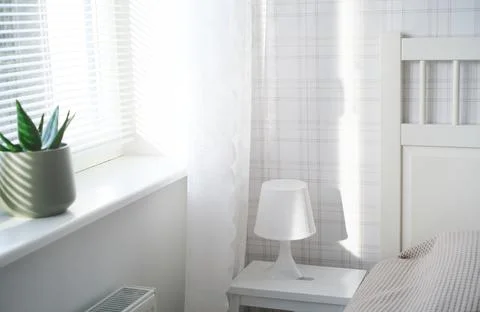 The interior of the room in white tones with a bed, bedside table, table lamp Stock Photos