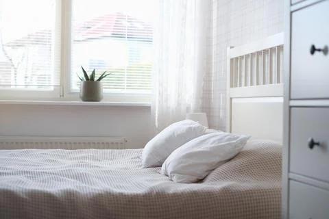 The interior of the room in white tones with a bed, bedside table, table lamp Stock Photos
