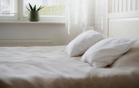 The interior of the room in white tones with a bed, bedside table, table lamp Stock Photos