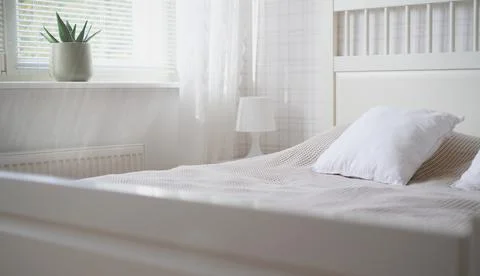 The interior of the room in white tones with a bed, bedside table, table lamp Stock Photos