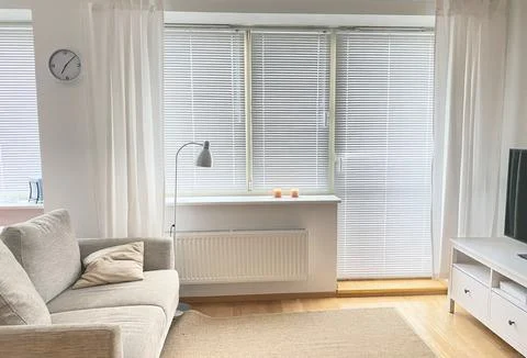 The interior of the room in white tones with a sofa, TV and bedside lamp Stock Photos