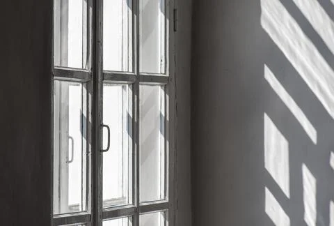 Interior of room with window, frame, sunlight and shadows on wall Stock Photos