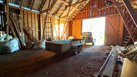 Interior of Rustic Wooden Farm Barn with Flatbed Trailer and SUV Parked Inside Stock Footage 333323015