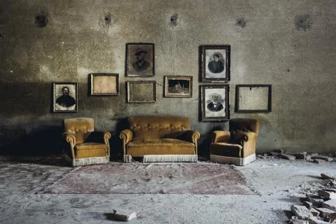 An interior shot of an abandoned building with sofas and various old photogra Stock Photos