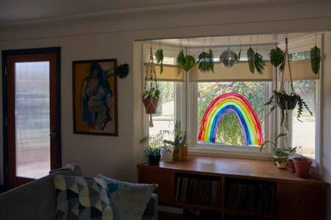 Interior shot of a rainbow painted on a window in a home as a sign of hope. Stock Photos