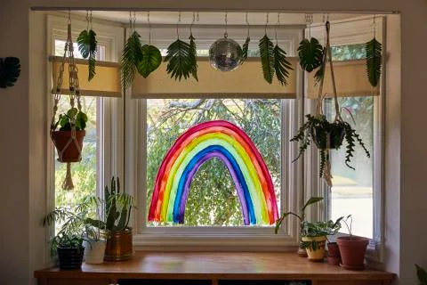Interior shot of a rainbow painted on a window in a home as a sign of hope. Stock Photos