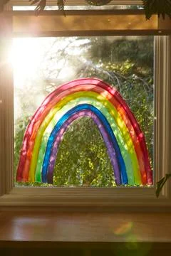 Interior shot of a rainbow painted on a window in a home as a sign of hope. Stock Photos