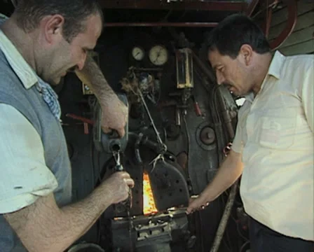 Interior of steam train engine room and workers Stock Footage