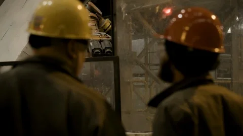 Interior Steel Factory - 2 workers reviewing robotic controls - Over the Stock Footage 89944214