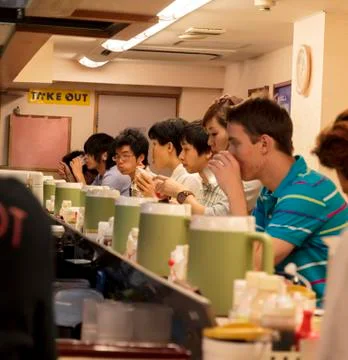 Interior of a street bar with a foreigner and a row of the japanese sittine a Stock Photos