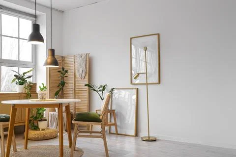 Interior of stylish dining room with table, houseplants, big window and glowi Stock Photos