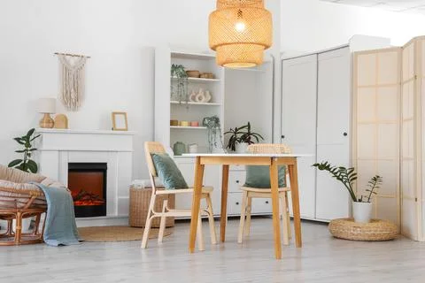 Interior of stylish dining room with table, armchair, fireplace and glowing l Stock Photos