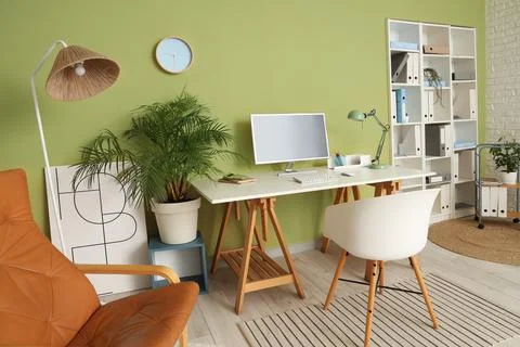 Interior of stylish home office with computer, workplace and clock hanging on Stock Photos