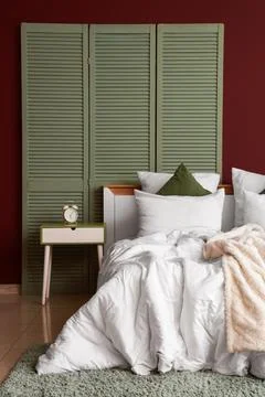 Interior of stylish room with bed, table and green folding screen Stock Photos