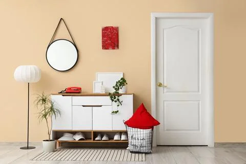 Interior of stylish room with commode, mirror and lamp Stock Photos