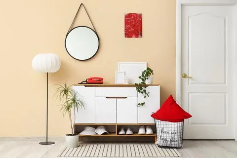 Interior of stylish room with commode, mirror and lamp Stock Photos