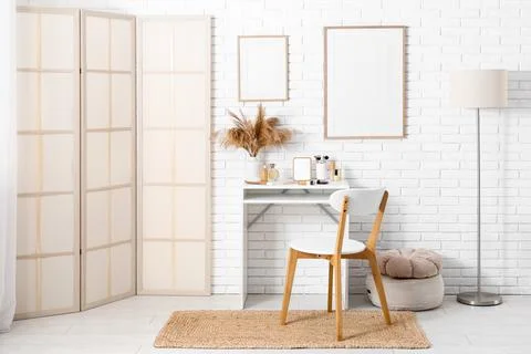 Interior of stylish room with makeup table, lamp and folding screen Stock Photos