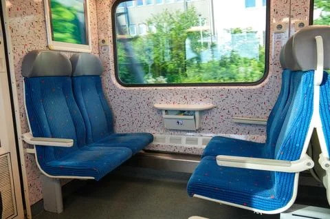 Interior of a train with blue seats and a white seat. Stock Photos