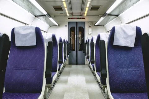 Interior of train carriage between rows of empty chairs Stock Photos