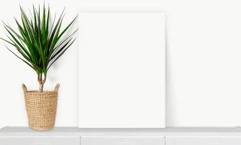 Interior vertical rectangular poster mockup standing on the table with plant  Stock Photos