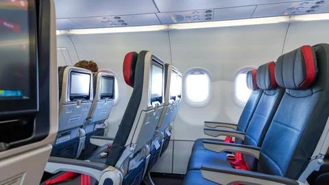 Interior view of an airplane cabin showcasing empty seats with red accents Stock Photos