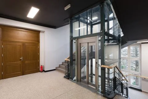 Interior View of a Building with Glass Elevator and Wooden Doors Stock Photos