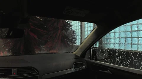 Interior view from a car during a wash, showing brushes and soap bubbles on the Stock Footage 333799052