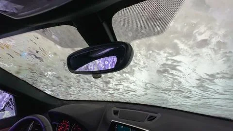 Interior view of a car windshield covered in soapy water during a car wash. Stock Photos