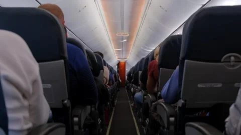 Interior view of crowded commercial airplane cabin with passengers sitting .. Stock Footage 338332387