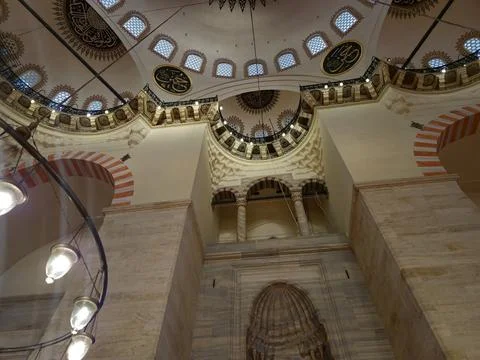 Interior view of a decorated mosque with ornate ceiling lights Stock Photos